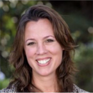 The image depicts a person with wavy, shoulder-length hair and a background with blurred, natural foliage.